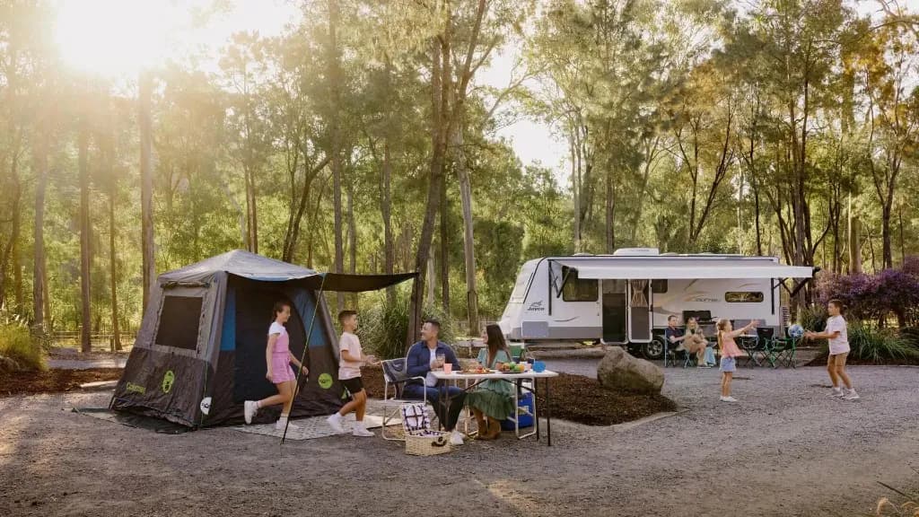 A family set up at a bush campsite beside their caravan and tent